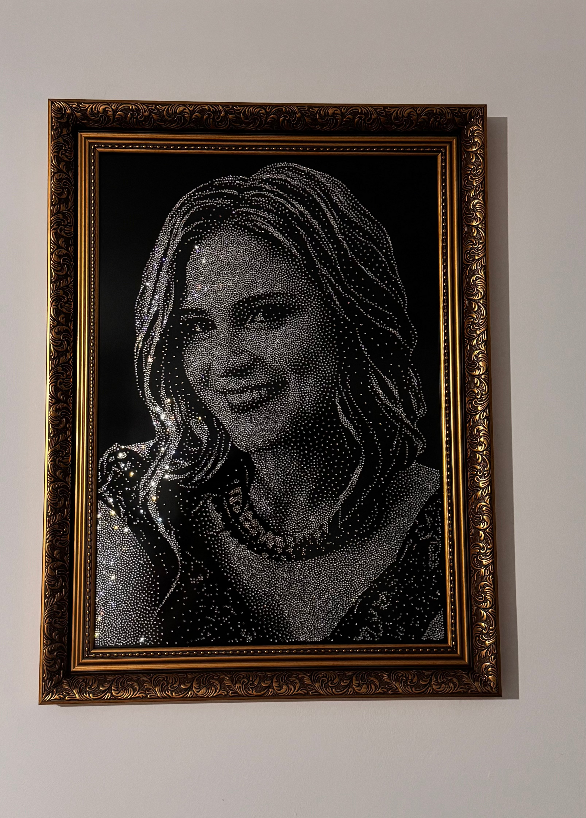 Framed portrait of a woman with rhinestones on a white wall