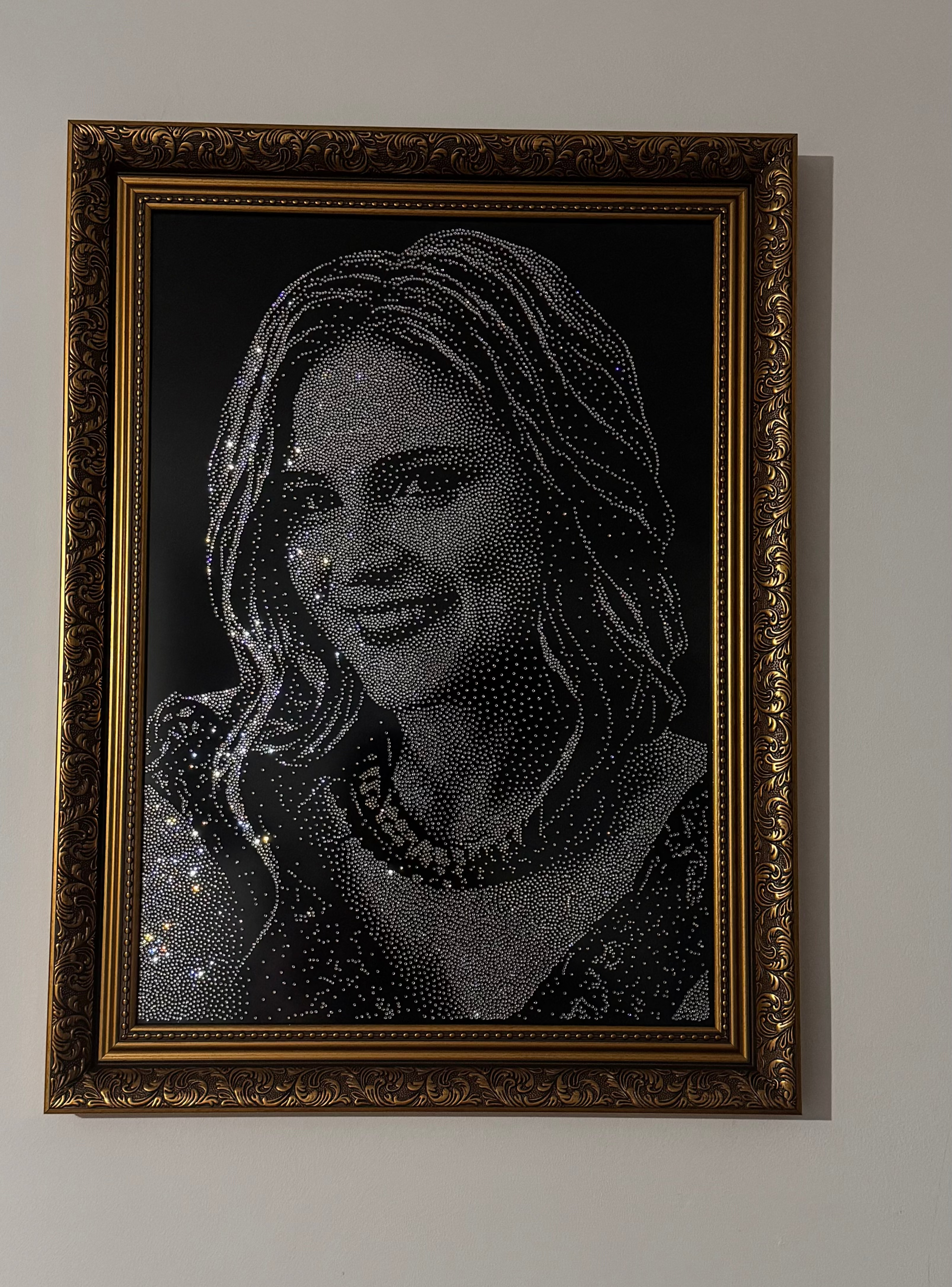 Framed portrait of a woman made from rhinestones on a white wall