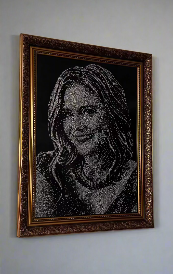 Framed portrait with rhinestones of a woman on a white wall